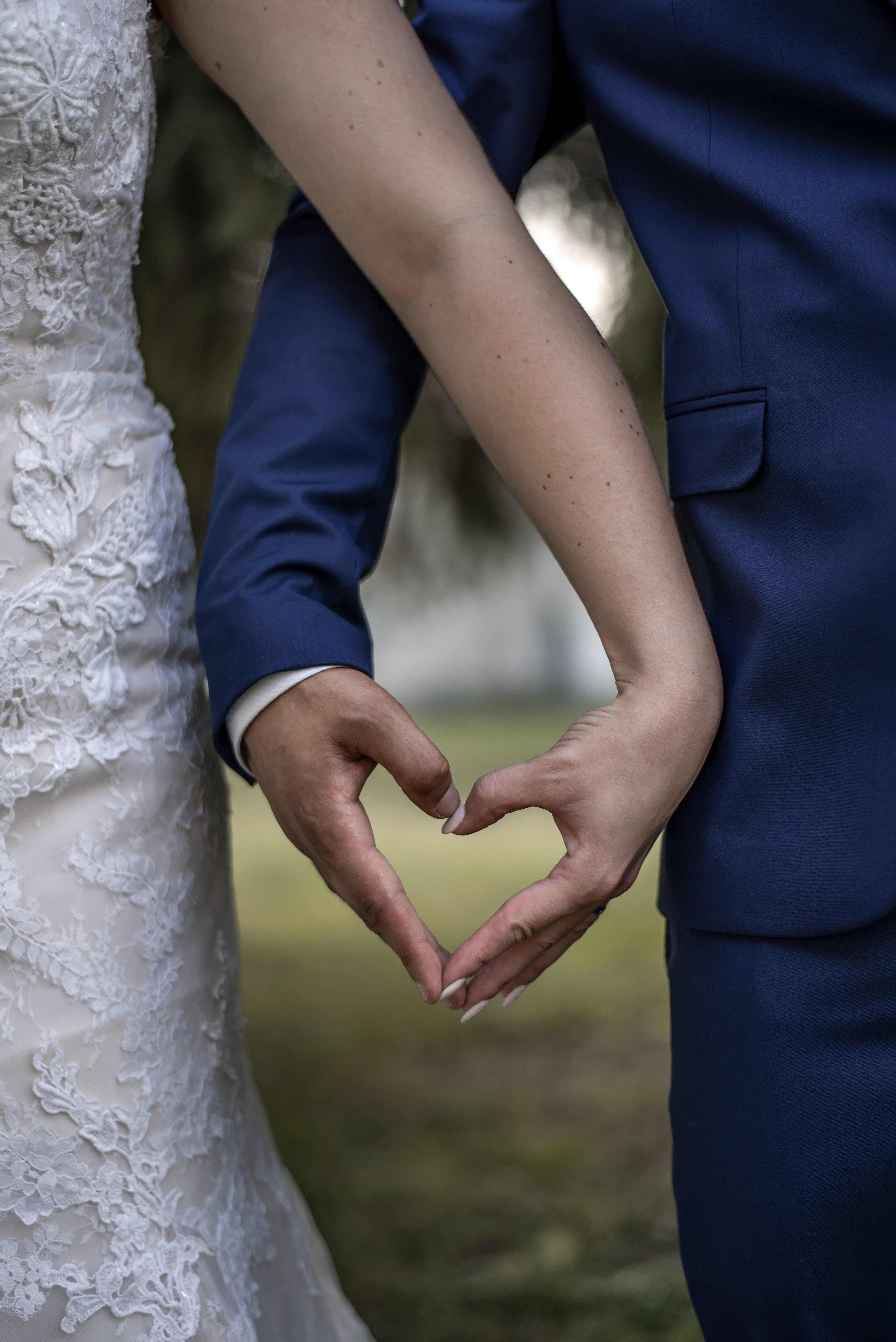 vertical-closeup-shot-bride-groom-forming-heart-with-their-hands